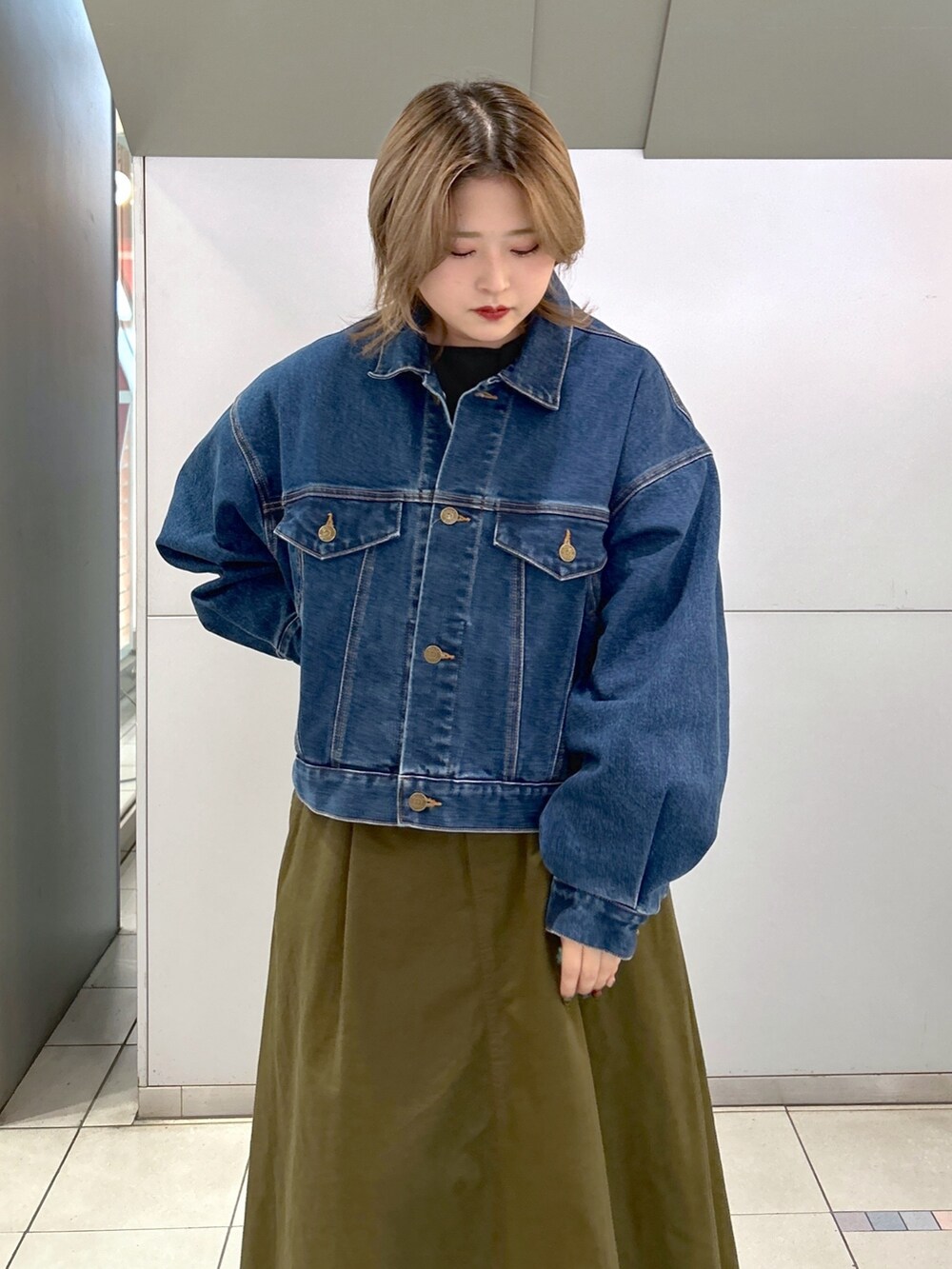 グリーン系のジャンパースカート、ブラック系のブーツ、ブルー系のデニムジャケットを着用したレディースの冬コーディネートの4枚目の写真