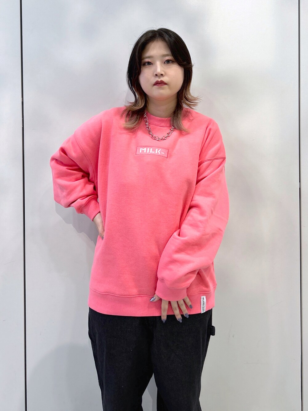 ピンク系のスウェット、ブラック系のサロペット/オーバーオール、ベージュ系のスニーカーを着用したレディースの秋コーディネートの5枚目の写真