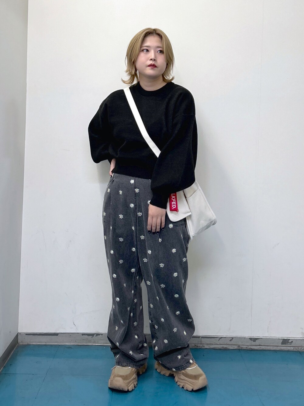 ブラック系のニット/セーター、ブラック系のデニムパンツ、レッド系のショルダーバッグを着用したレディースの秋コーディネートの2枚目の写真