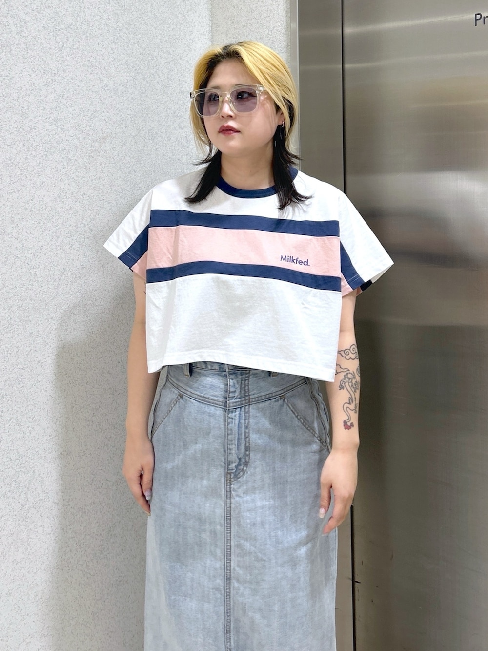 ホワイト系のTシャツ/カットソー、ブルー系のデニムスカート、ホワイト系のショルダーバッグを着用したレディースの春コーディネートの4枚目の写真