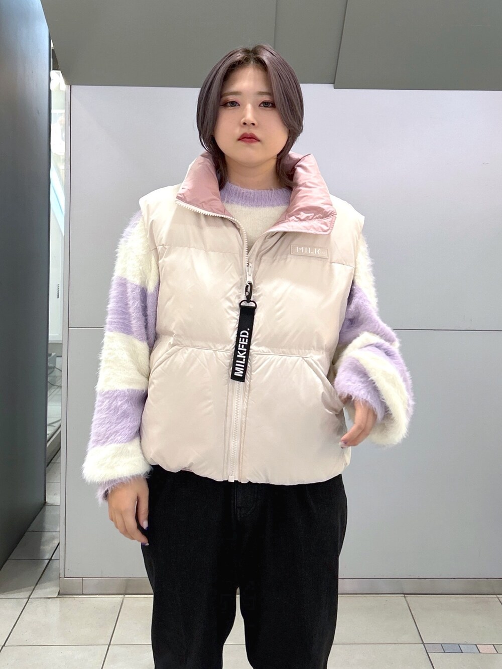 ブラック系のデニムパンツ、ベージュ系のスニーカー、ホワイト系のダウンベストを着用したレディースの秋コーディネートの5枚目の写真