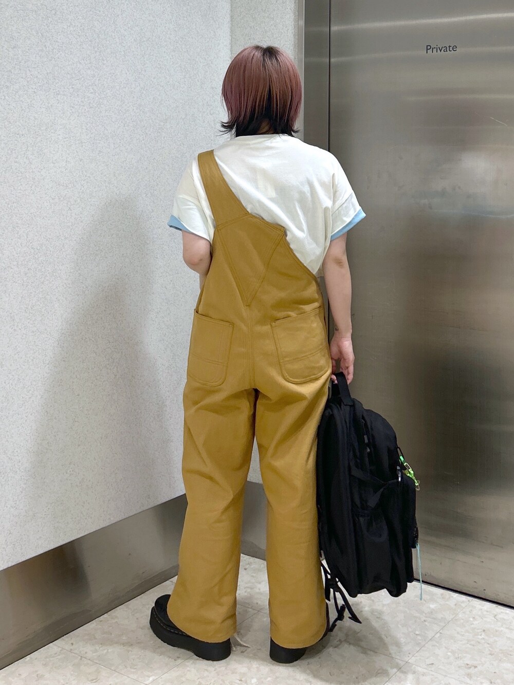 ベージュ系のサロペット/オーバーオール、ホワイト系のTシャツ/カットソー、ブラック系のブーツを着用したレディースの夏コーディネートの4枚目の写真