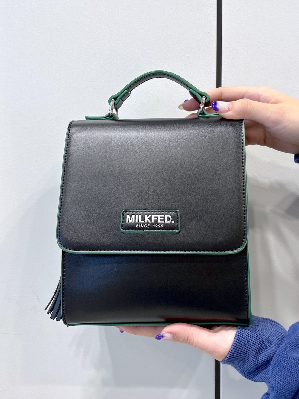 ブルー系のパーカー、ブラック系のスカート、ブラック系のショルダーバッグを着用したレディースの秋コーディネートの5枚目の写真