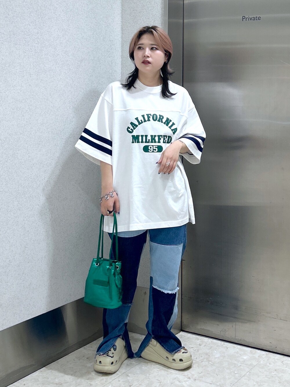 ブルー系のデニムパンツ、グリーン系のショルダーバッグ、ベージュ系のサンダルを着用したレディースの夏コーディネートの2枚目の写真