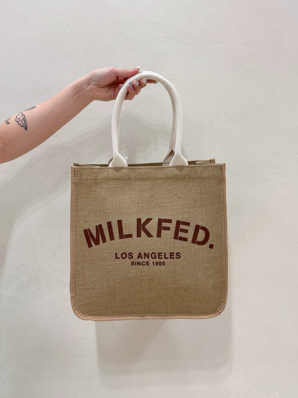 ホワイト系のTシャツ/カットソー、ブルー系のデニムスカート、ベージュ系のトートバッグを着用したレディースの春コーディネートの7枚目の写真