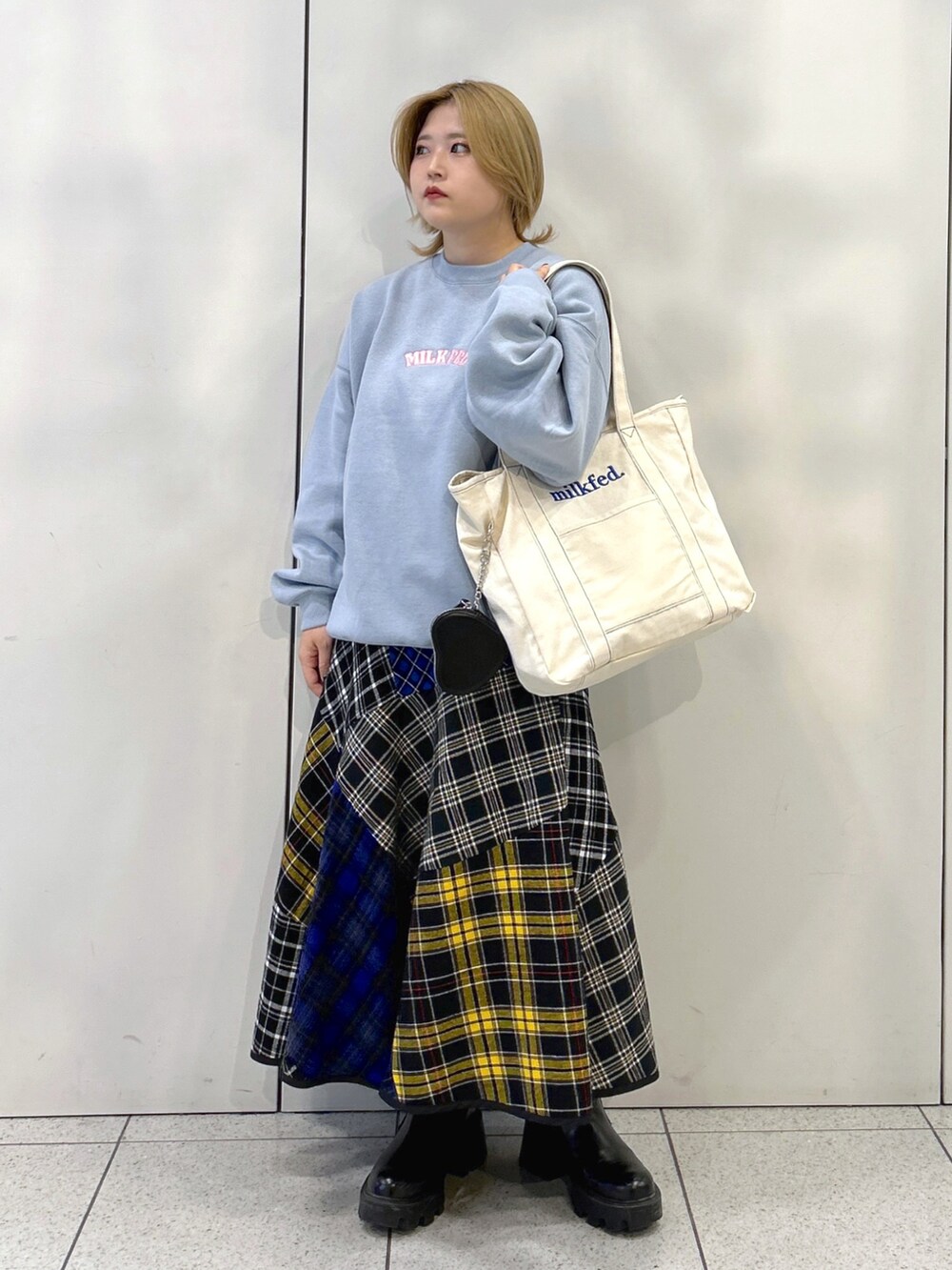 ブルー系のスウェット、ブルー系のトートバッグ、ブラック系のスカートを着用したレディースの秋コーディネートの2枚目の写真