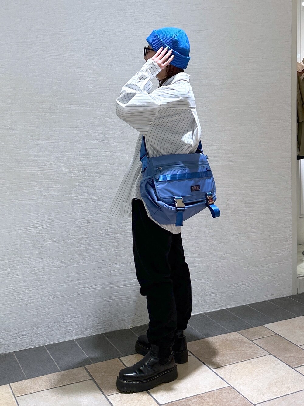 ホワイト系のシャツ/ブラウス、ブルー系のメッセンジャーバッグ、ブラック系のスウェットパンツを着用したレディースの冬コーディネートの4枚目の写真