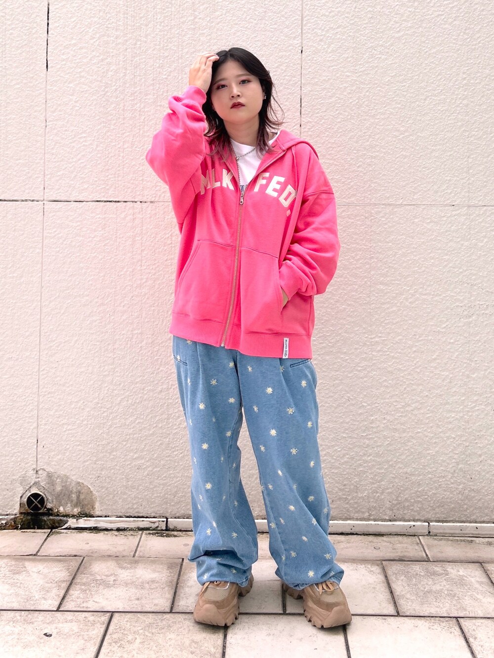 ピンク系のパーカー、ブルー系のデニムパンツ、ベージュ系のスニーカーを着用したレディースの秋コーディネートの2枚目の写真