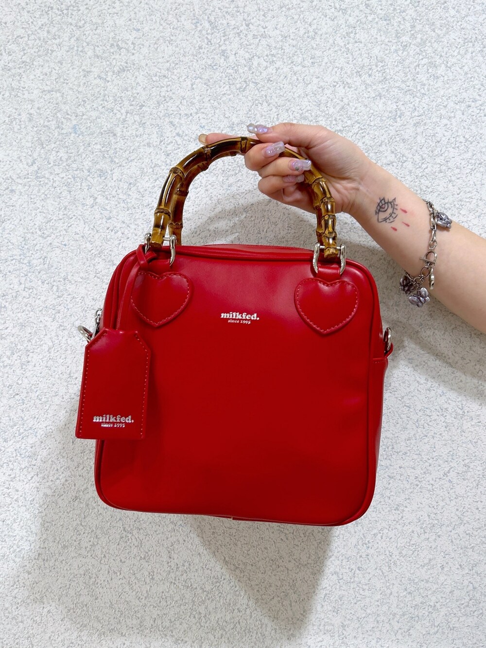 レッド系のショルダーバッグ、ブラック系のサロペット/オーバーオール、ホワイト系のTシャツ/カットソーを着用したレディースの春コーディネートの5枚目の写真