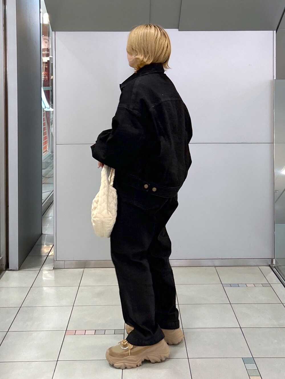 ブラック系のデニムジャケット、グリーン系のTシャツ/カットソー、ブラック系のデニムパンツを着用したレディースの秋コーディネートの3枚目の写真