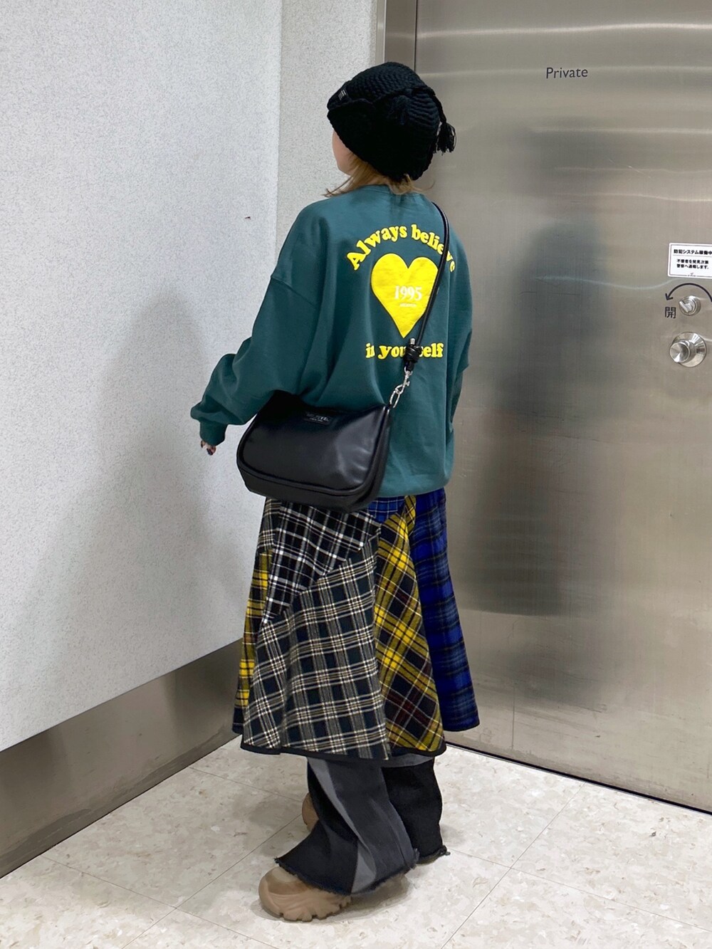 グリーン系のスウェット、ブラック系のショルダーバッグ、ブラック系のスカートを着用したレディースの冬コーディネートの3枚目の写真