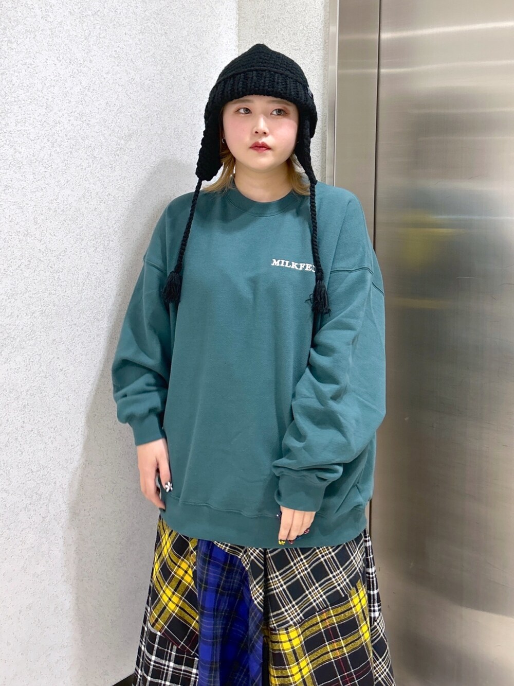 グリーン系のスウェット、ブラック系のショルダーバッグ、ブラック系のスカートを着用したレディースの冬コーディネートの4枚目の写真