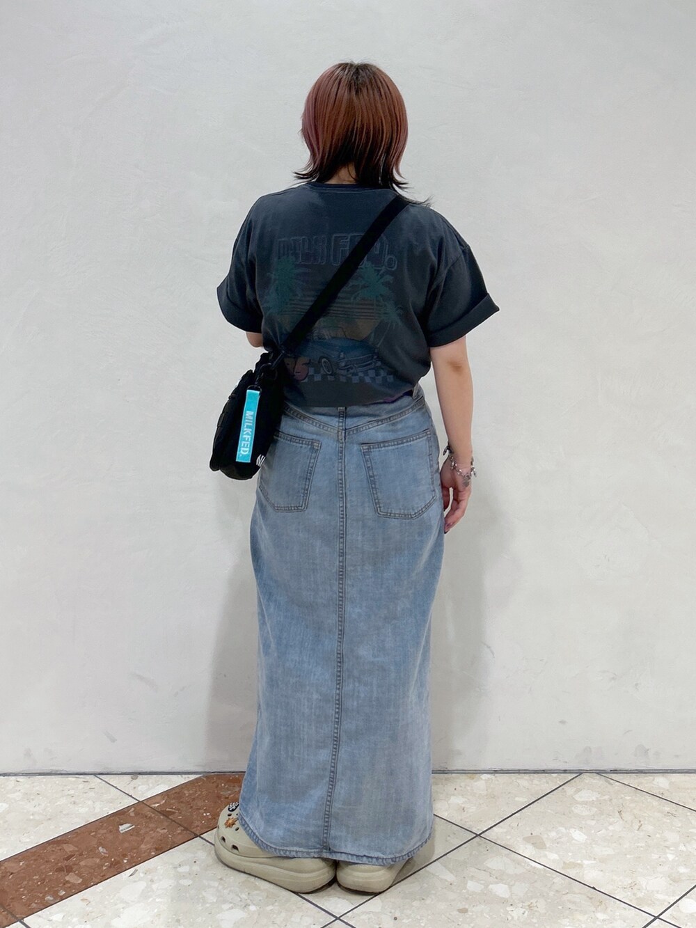 グレー系のTシャツ/カットソー、グリーン系のショルダーバッグ、ブルー系のデニムスカートを着用したレディースの夏コーディネートの3枚目の写真