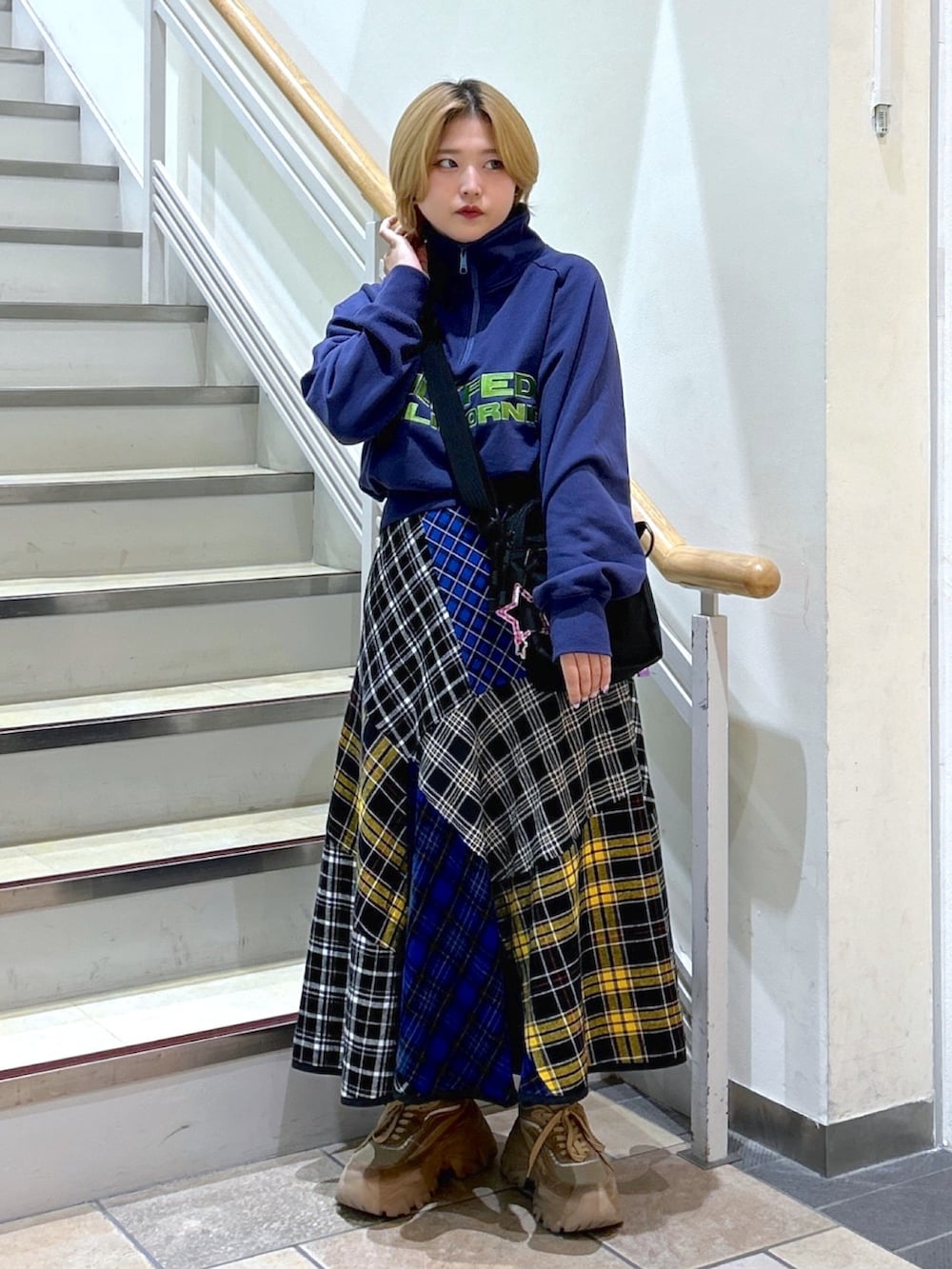 ブルー系のスウェット、ブラック系のスカート、パープル系のショルダーバッグを着用したレディースの秋コーディネートの2枚目の写真