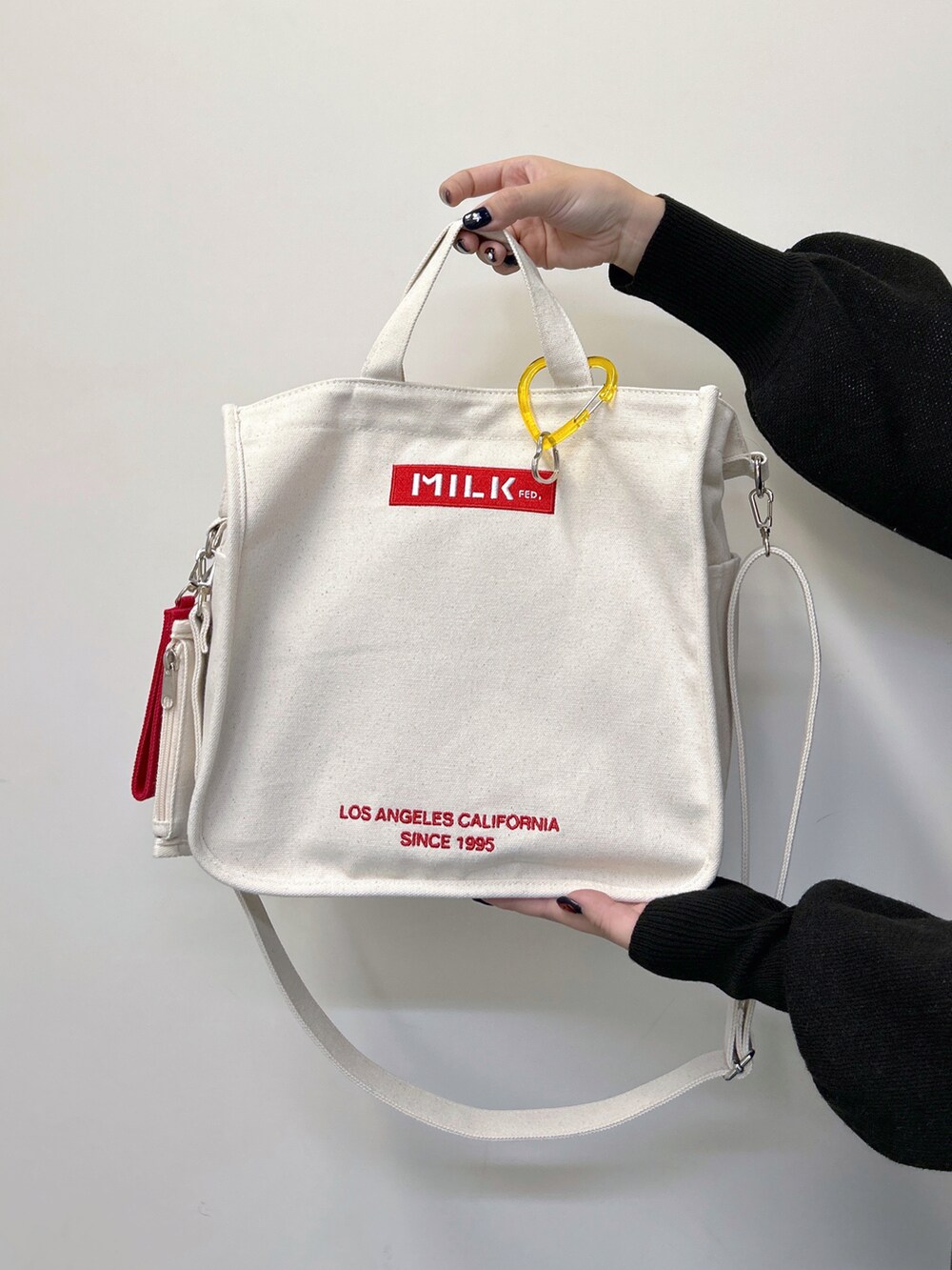 ブラック系のニット/セーター、ブラック系のデニムパンツ、レッド系のショルダーバッグを着用したレディースの秋コーディネートの4枚目の写真