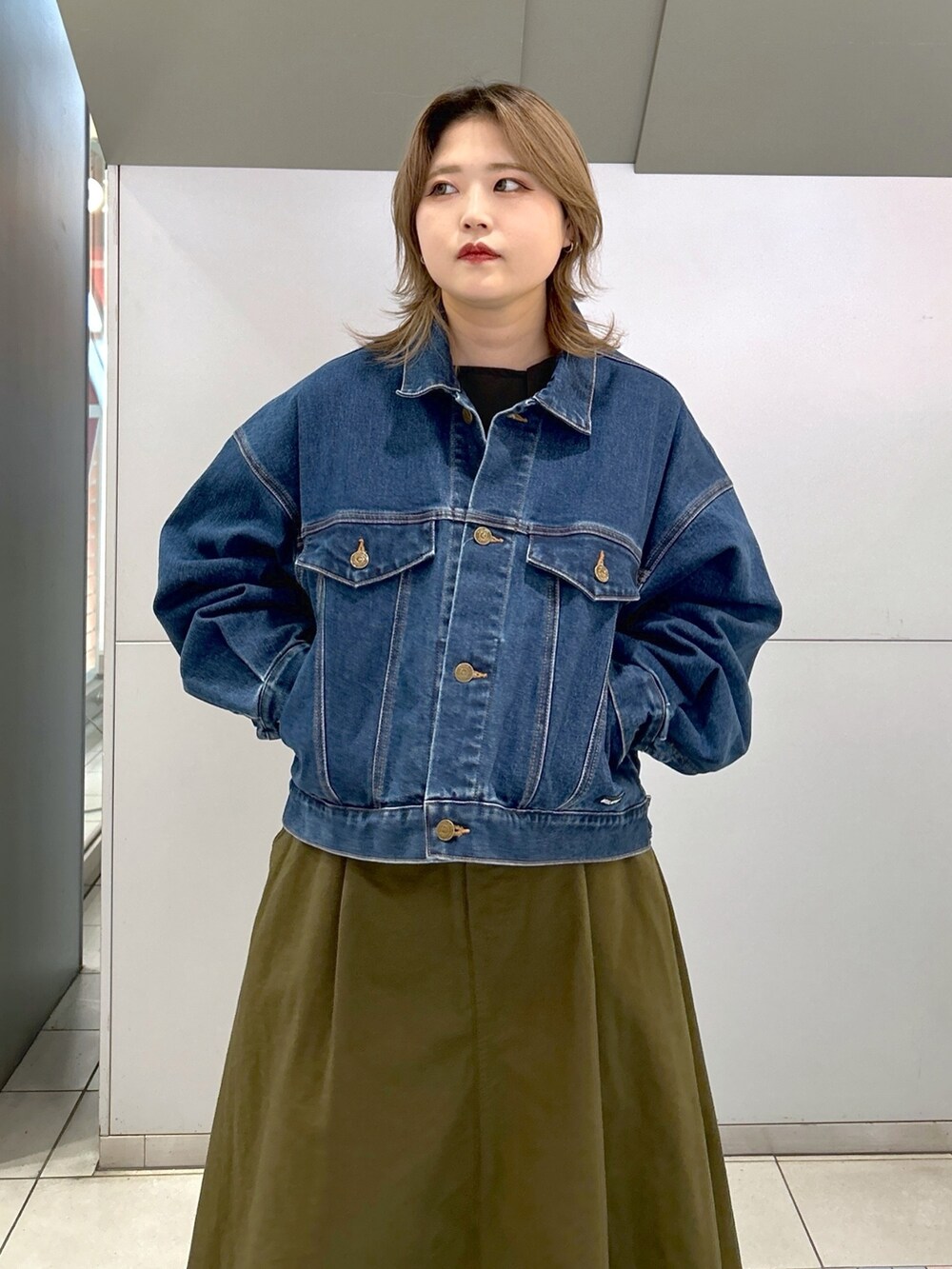 グリーン系のジャンパースカート、ブラック系のブーツ、ブルー系のデニムジャケットを着用したレディースの冬コーディネートの5枚目の写真