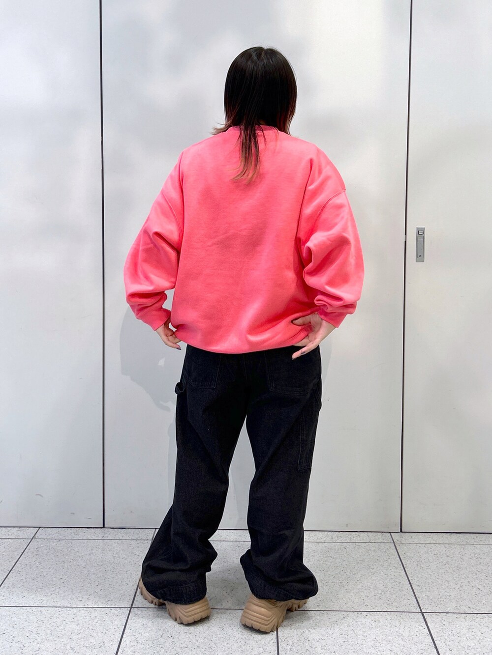 ピンク系のスウェット、ブラック系のサロペット/オーバーオール、ベージュ系のスニーカーを着用したレディースの秋コーディネートの3枚目の写真