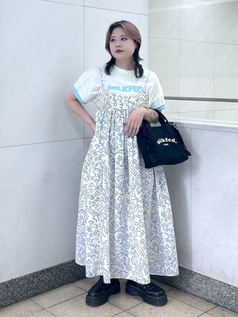 ホワイト系のワンピース、ブラック系のショルダーバッグ、ブラック系のブーツを着用したレディースの夏コーディネートの2枚目の写真