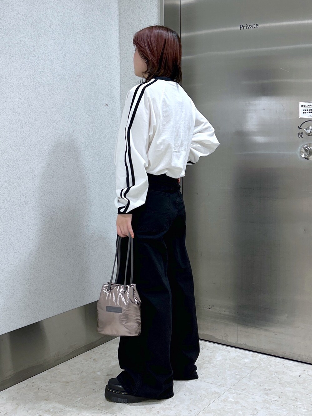 ホワイト系のTシャツ/カットソー、ブラック系のデニムパンツ、シルバー系のショルダーバッグを着用したレディースの冬コーディネートの3枚目の写真