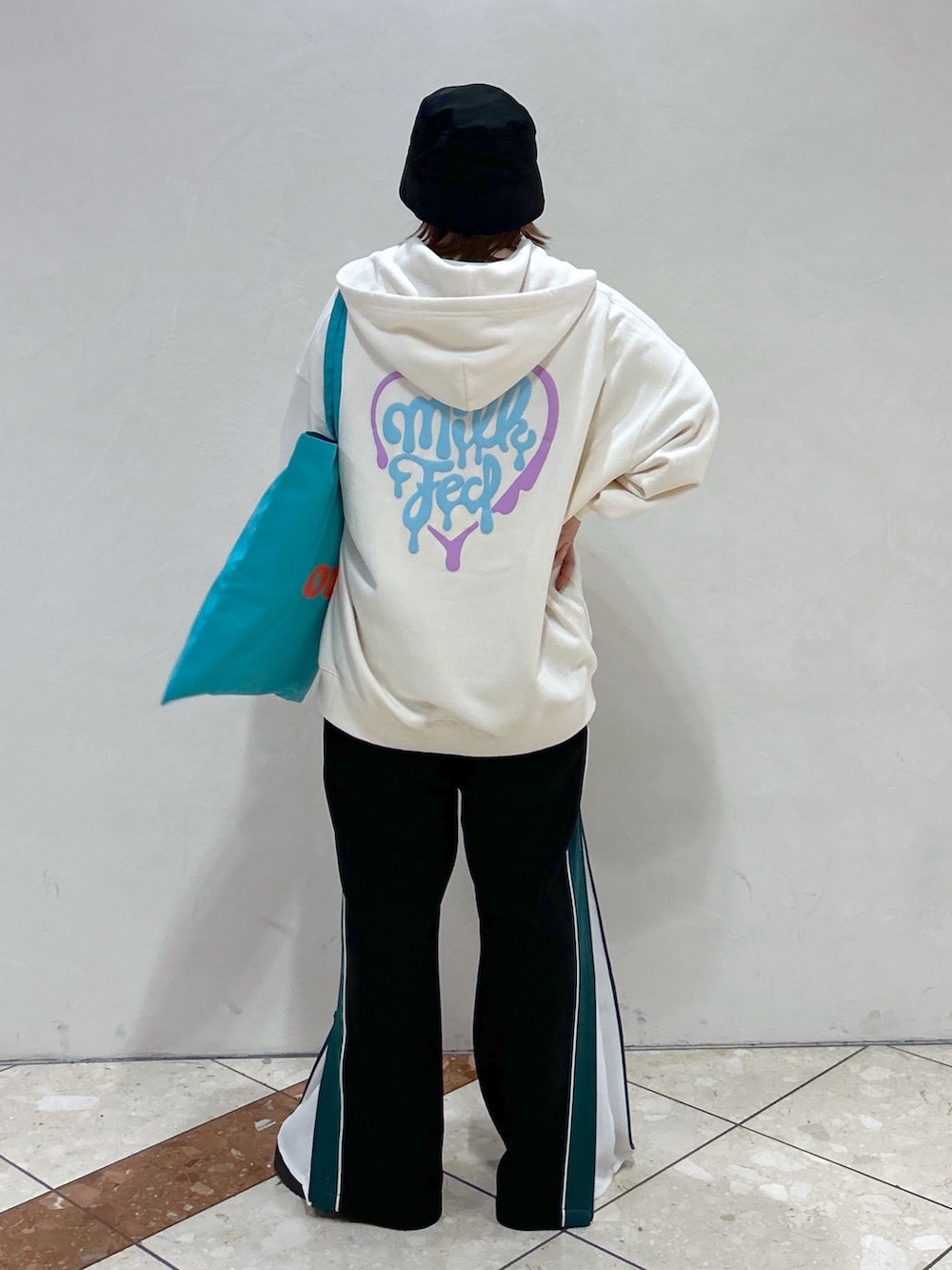 ホワイト系のパーカー、ブラック系のその他パンツ、グリーン系のトートバッグを着用したレディースの春コーディネートの2枚目の写真