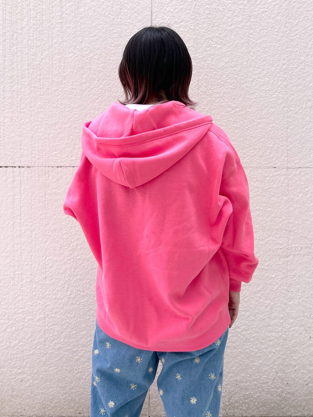 ピンク系のパーカー、ブルー系のデニムパンツ、ベージュ系のスニーカーを着用したレディースの秋コーディネートの4枚目の写真