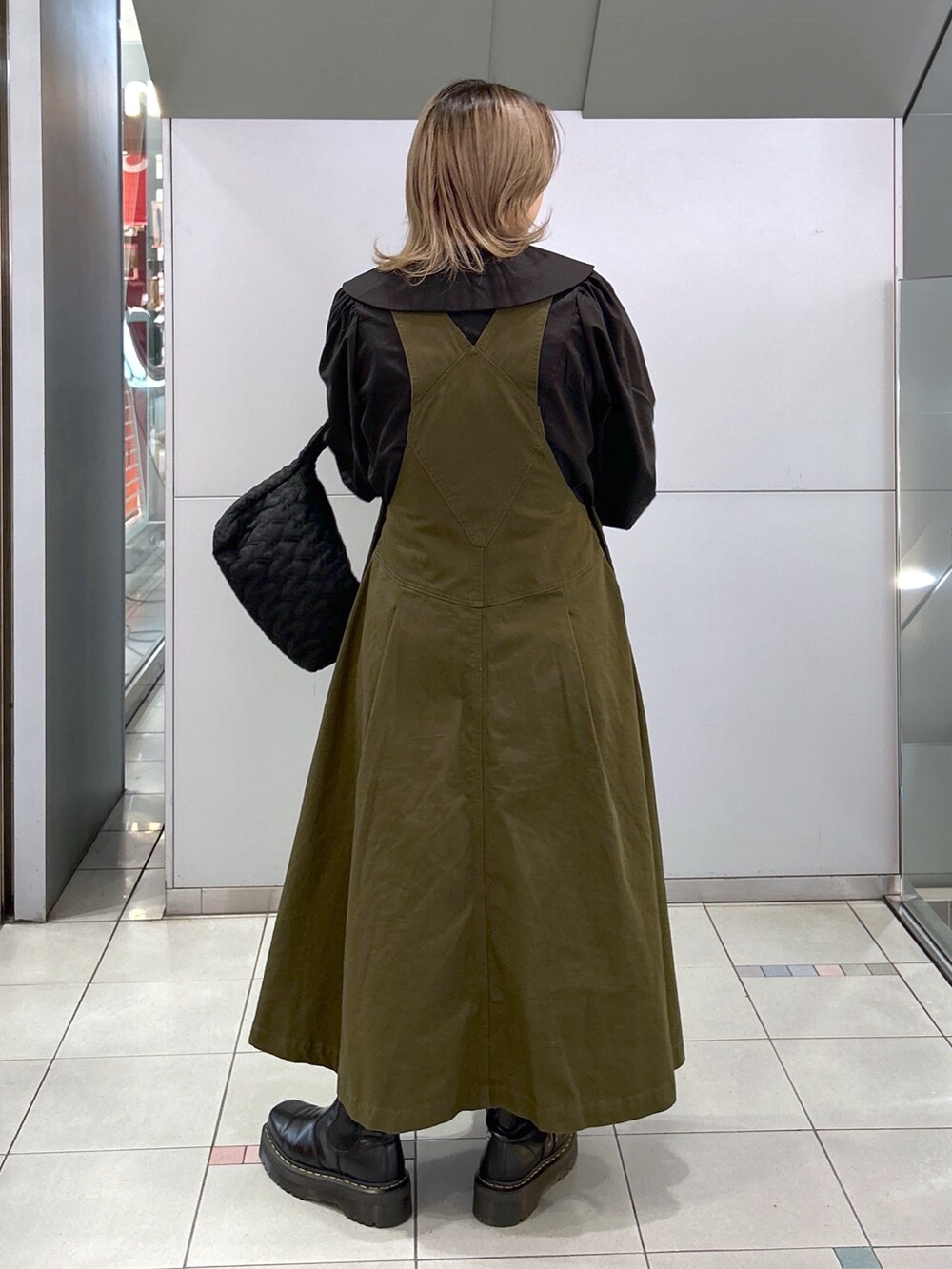 ブラック系のシャツ/ブラウス、グリーン系のジャンパースカート、ブラック系のブーツを着用したレディースの冬コーディネートの2枚目の写真