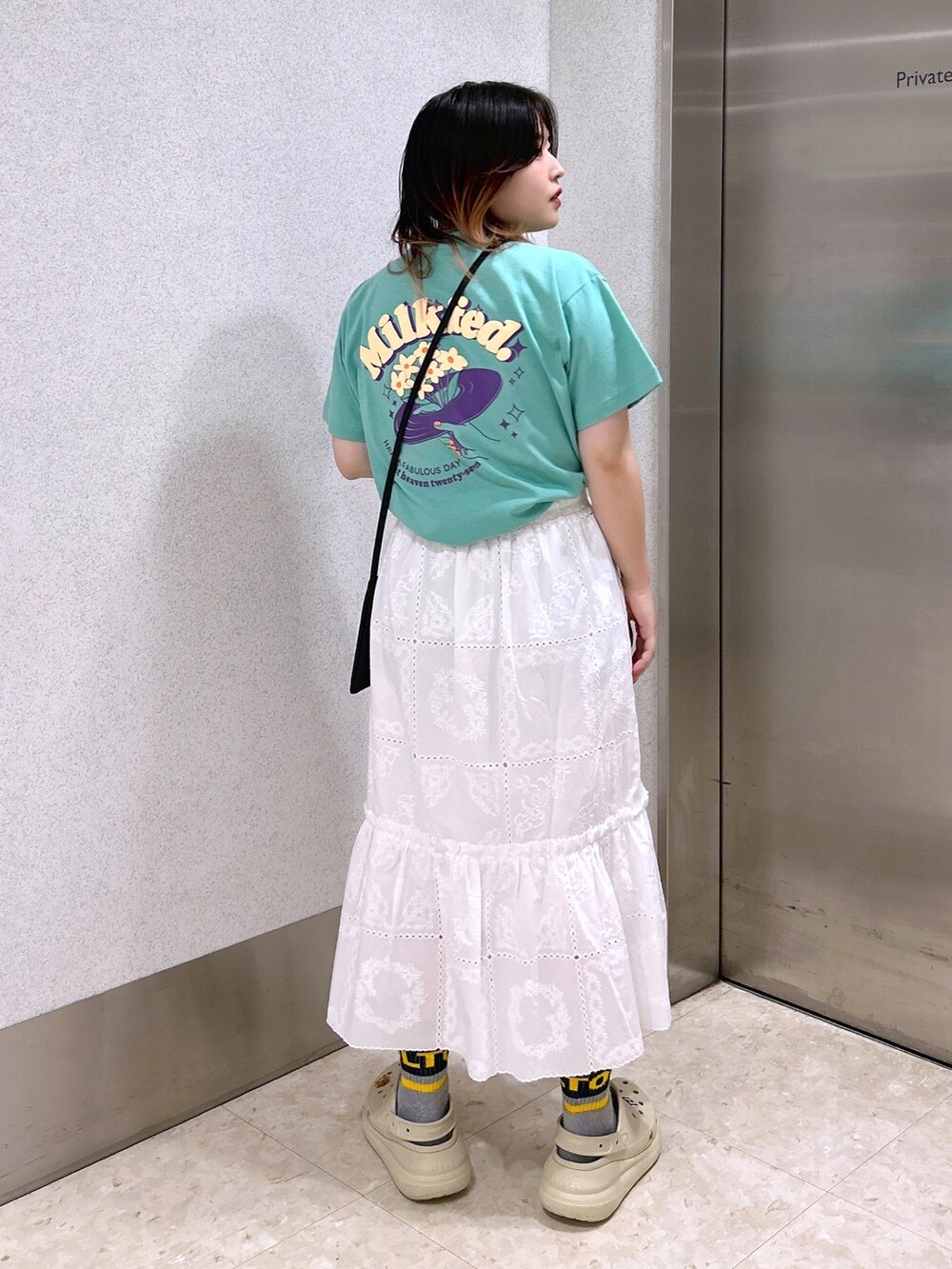 グリーン系のTシャツ/カットソー、ホワイト系のスカート、ベージュ系のサンダルを着用したレディースの夏コーディネートの3枚目の写真