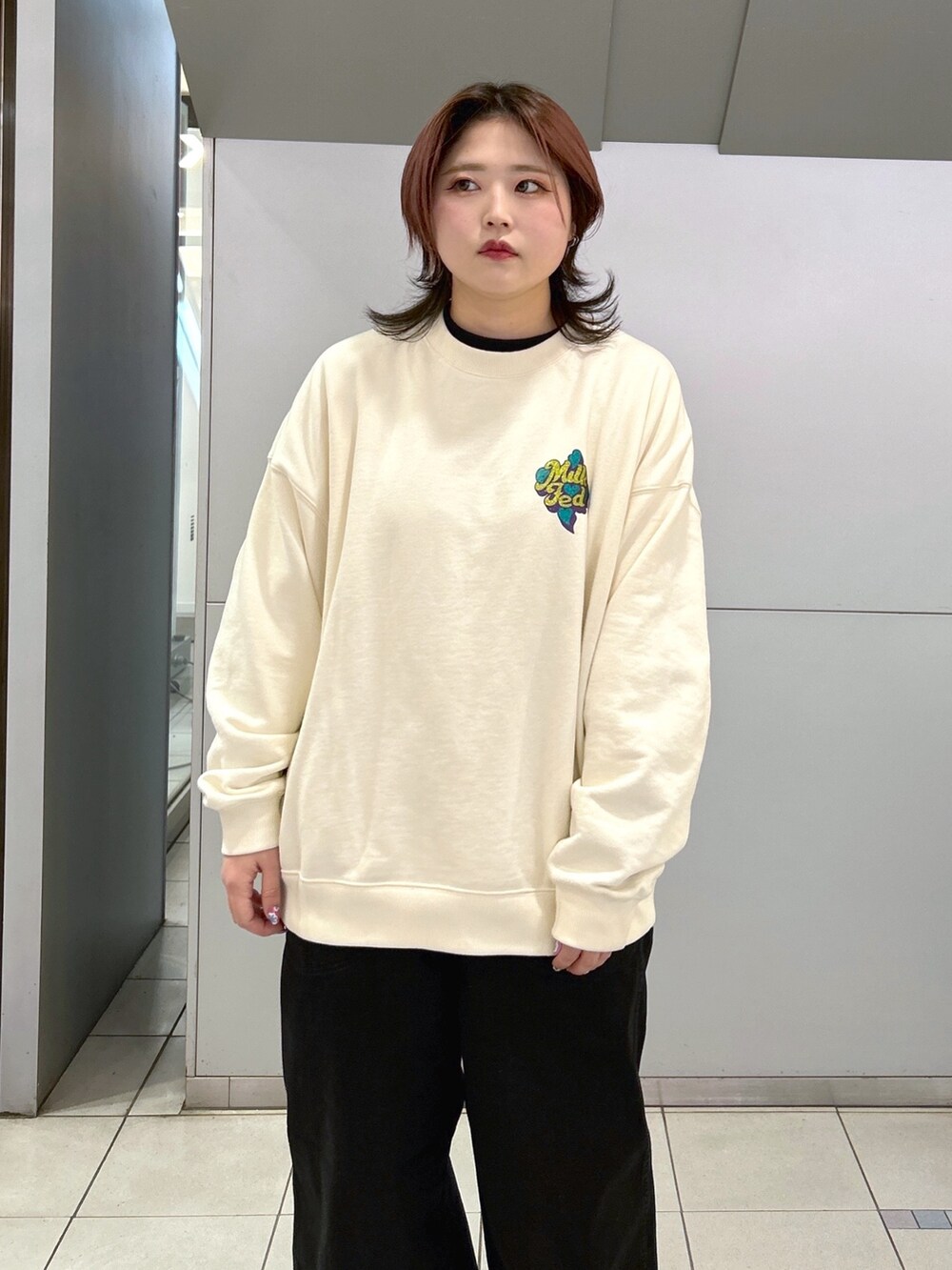ホワイト系のスウェット、ブラック系のデニムパンツ、パープル系のトートバッグを着用したレディースの冬コーディネートの3枚目の写真