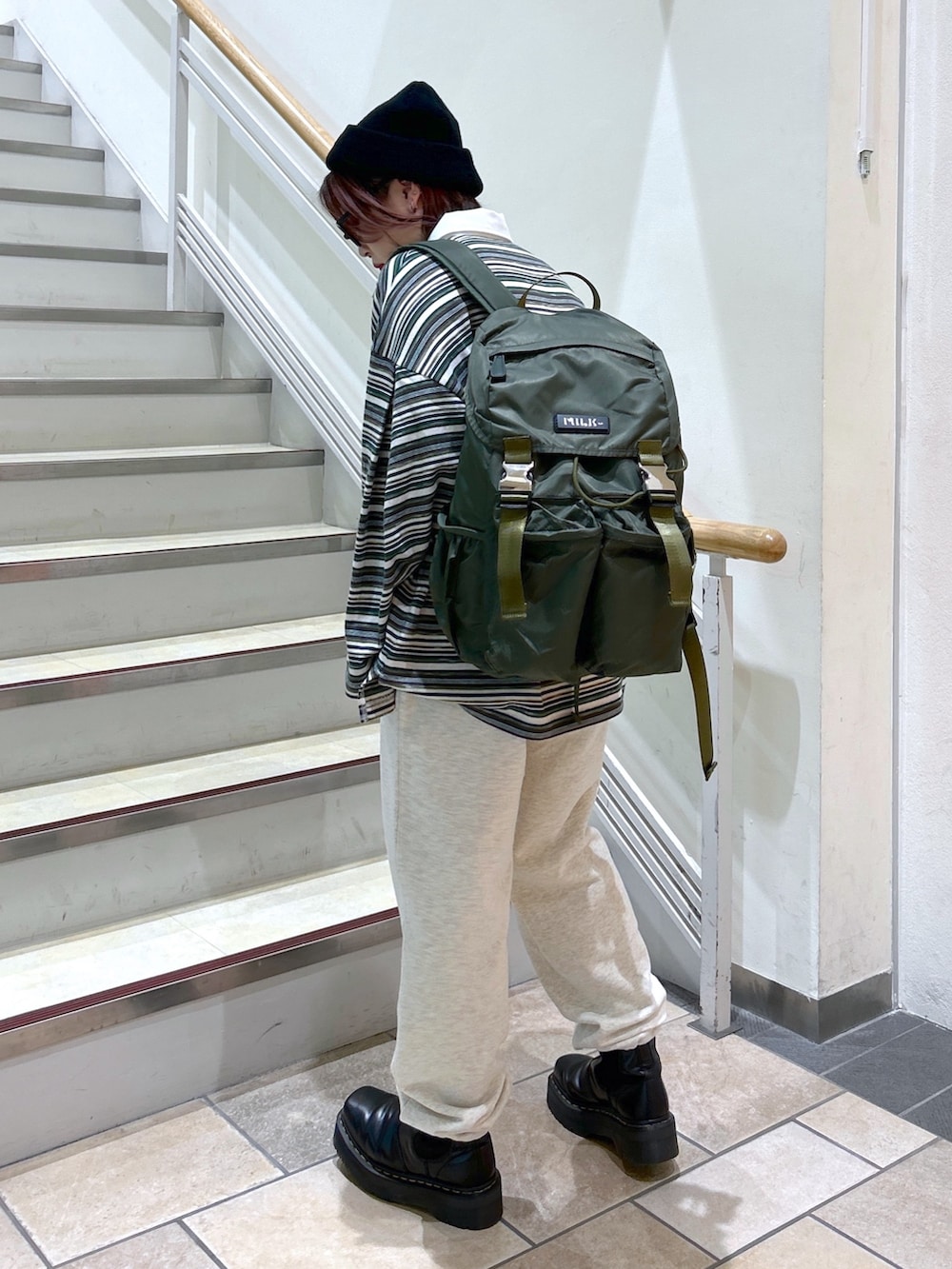 グリーン系のポロシャツ、ベージュ系のスウェットパンツ、グリーン系のバックパック/リュックを着用したレディースの冬コーディネートの4枚目の写真