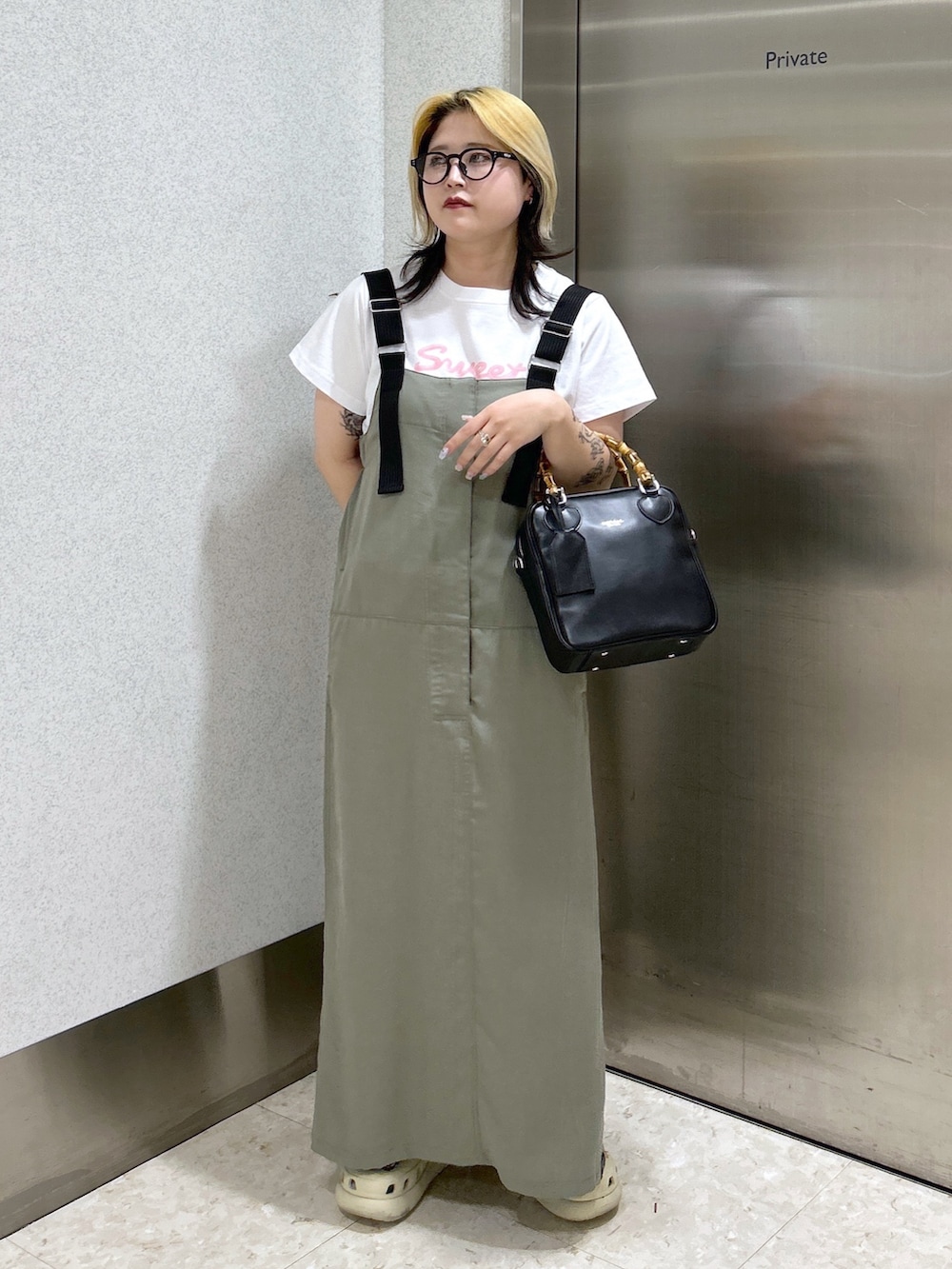 ブラック系のショルダーバッグ、ピンク系のTシャツ/カットソー、グリーン系のワンピースを着用したレディースの春コーディネートの3枚目の写真