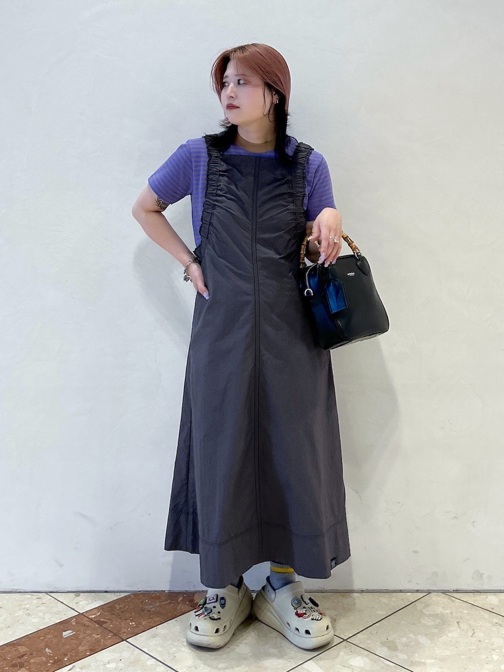 パープル系のTシャツ/カットソー、グレー系のワンピース、ブラック系のショルダーバッグを着用したレディースの春コーディネートの2枚目の写真