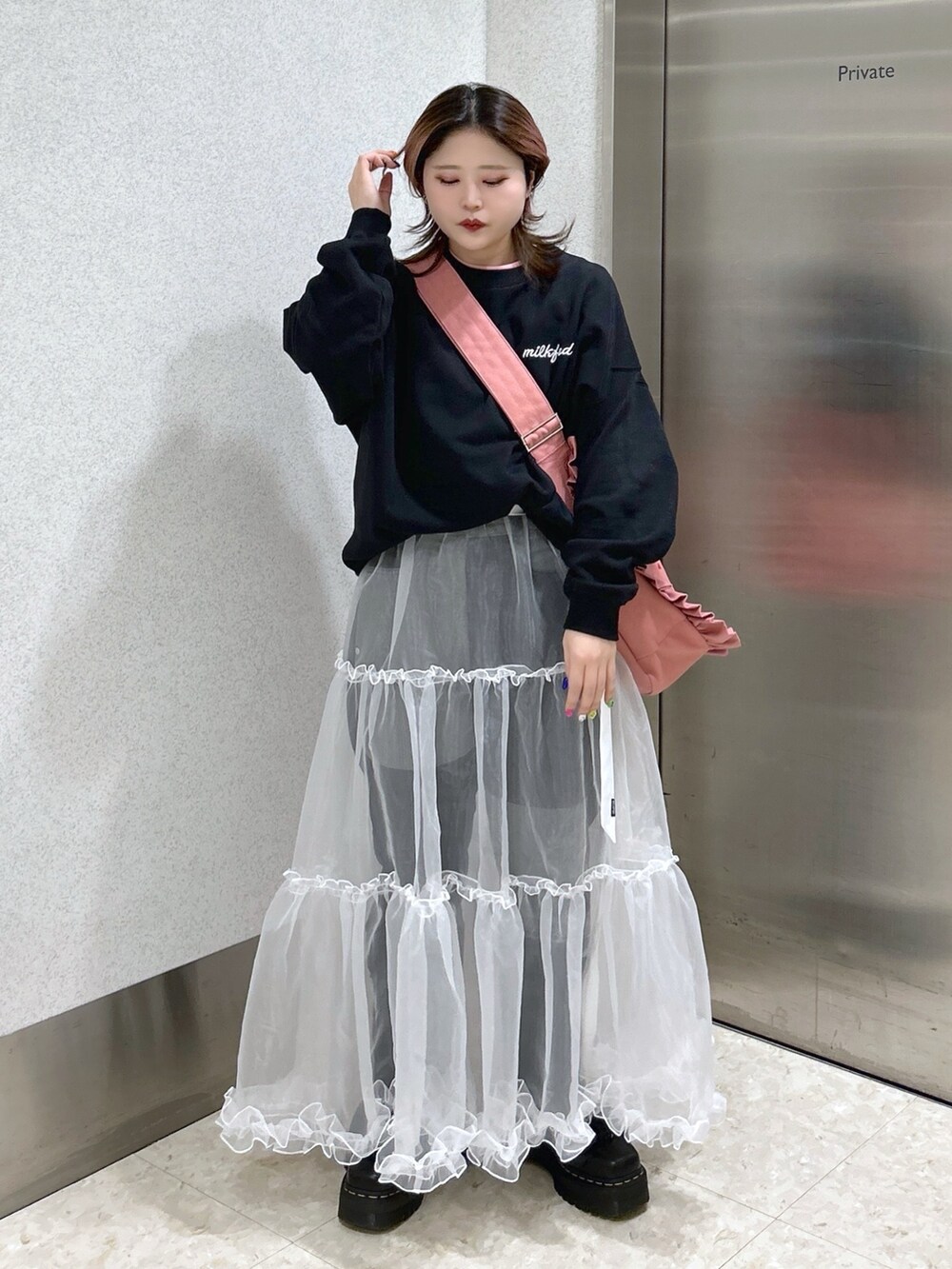 ブラック系のスウェット、ピンク系のショルダーバッグ、ブラック系のブーツを着用したレディースの春コーディネートの2枚目の写真