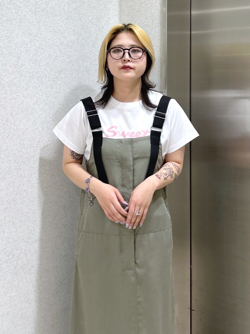 ブラック系のショルダーバッグ、ピンク系のTシャツ/カットソー、グリーン系のワンピースを着用したレディースの春コーディネートの5枚目の写真