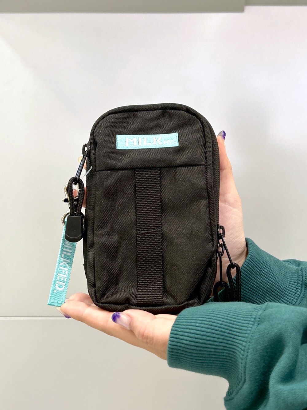 グリーン系のパーカー、グリーン系のショルダーバッグ、ブラック系のスカートを着用したレディースの秋コーディネートの4枚目の写真