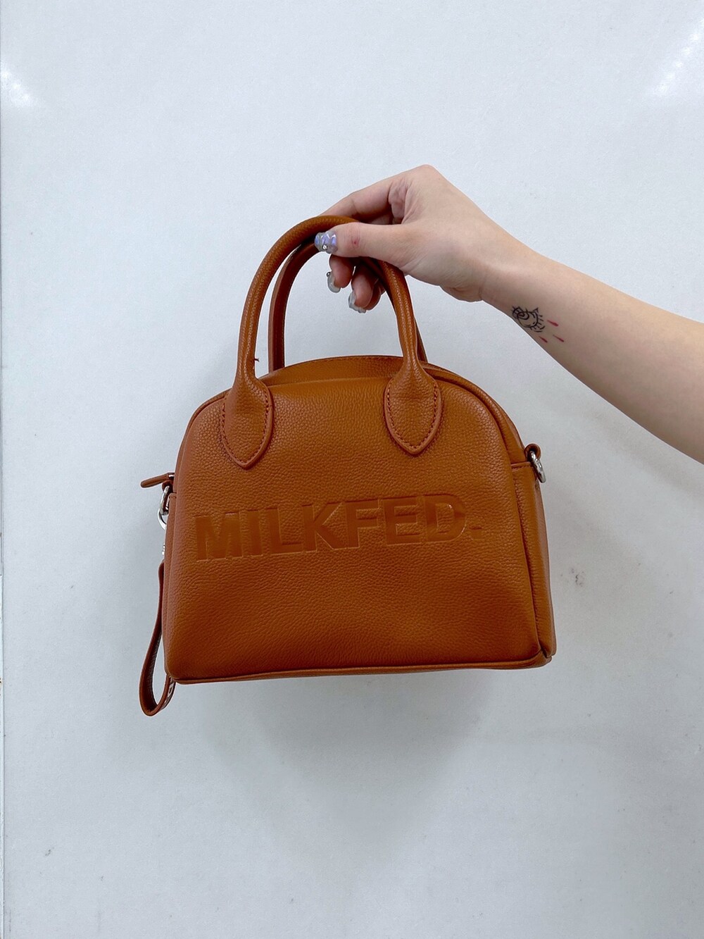 ブラック系のカーゴパンツ、ホワイト系のTシャツ/カットソー、ブラウン系のボストンバッグを着用したレディースの春コーディネートの5枚目の写真