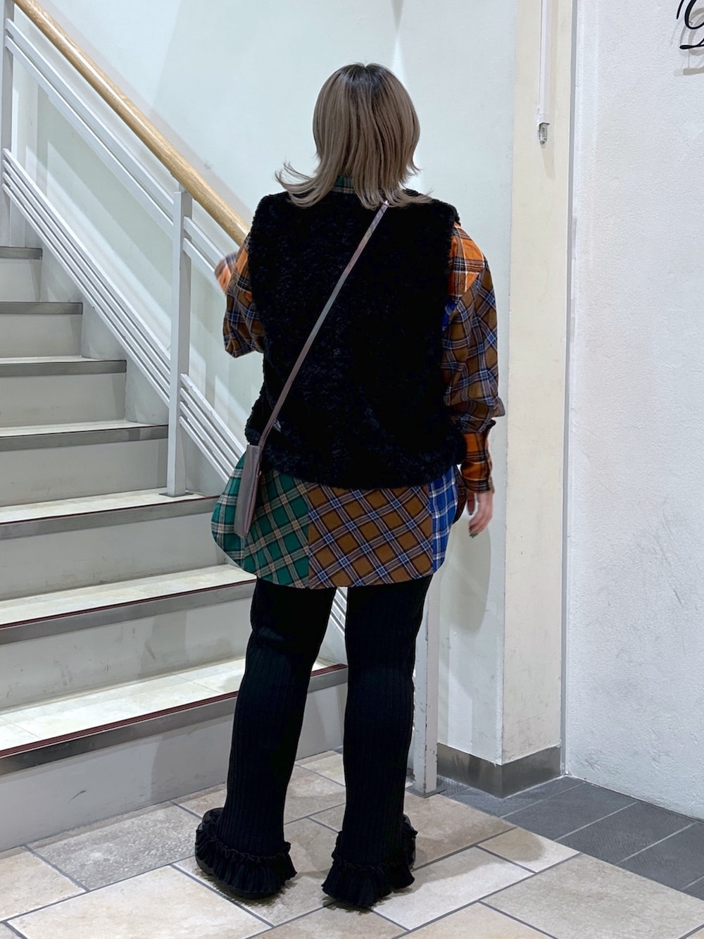 パープル系のショルダーバッグ、ブラック系のベスト、ブラウン系のシャツ/ブラウスを着用したレディースの冬コーディネートの2枚目の写真