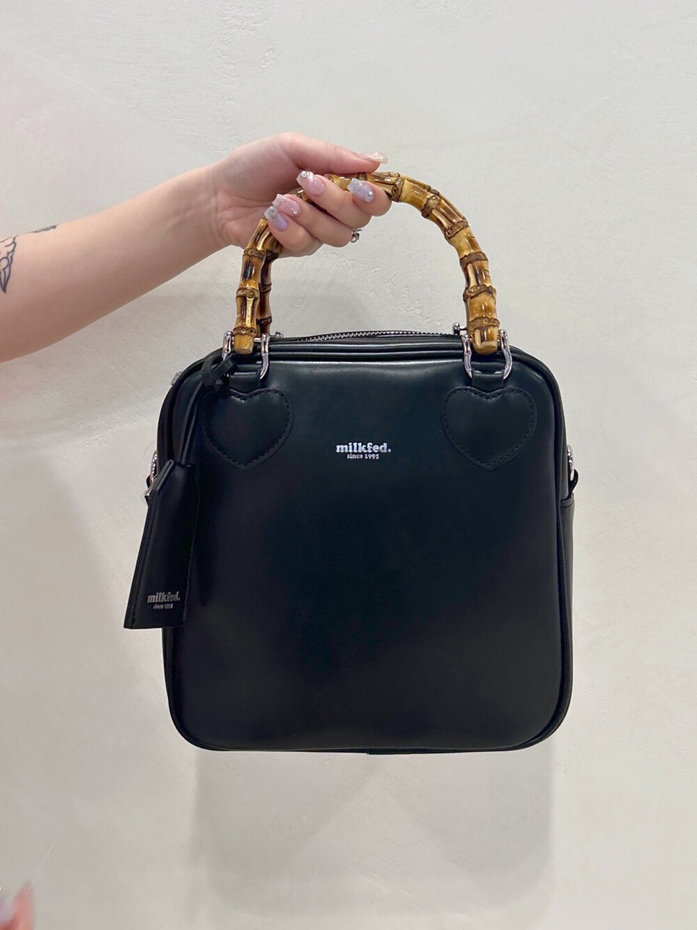 ブラック系のブーツ、ブラック系のスカート、ブラック系のショルダーバッグを着用したレディースの春コーディネートの6枚目の写真