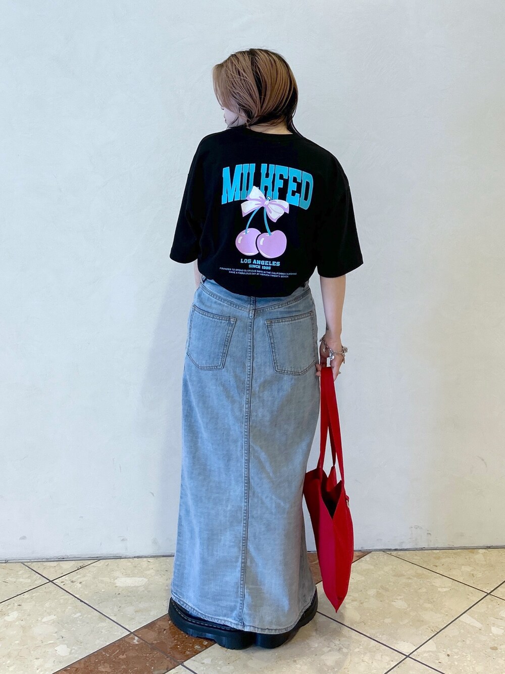 ブラック系のTシャツ/カットソー、ブルー系のデニムスカート、レッド系のトートバッグを着用したレディースの夏コーディネートの4枚目の写真