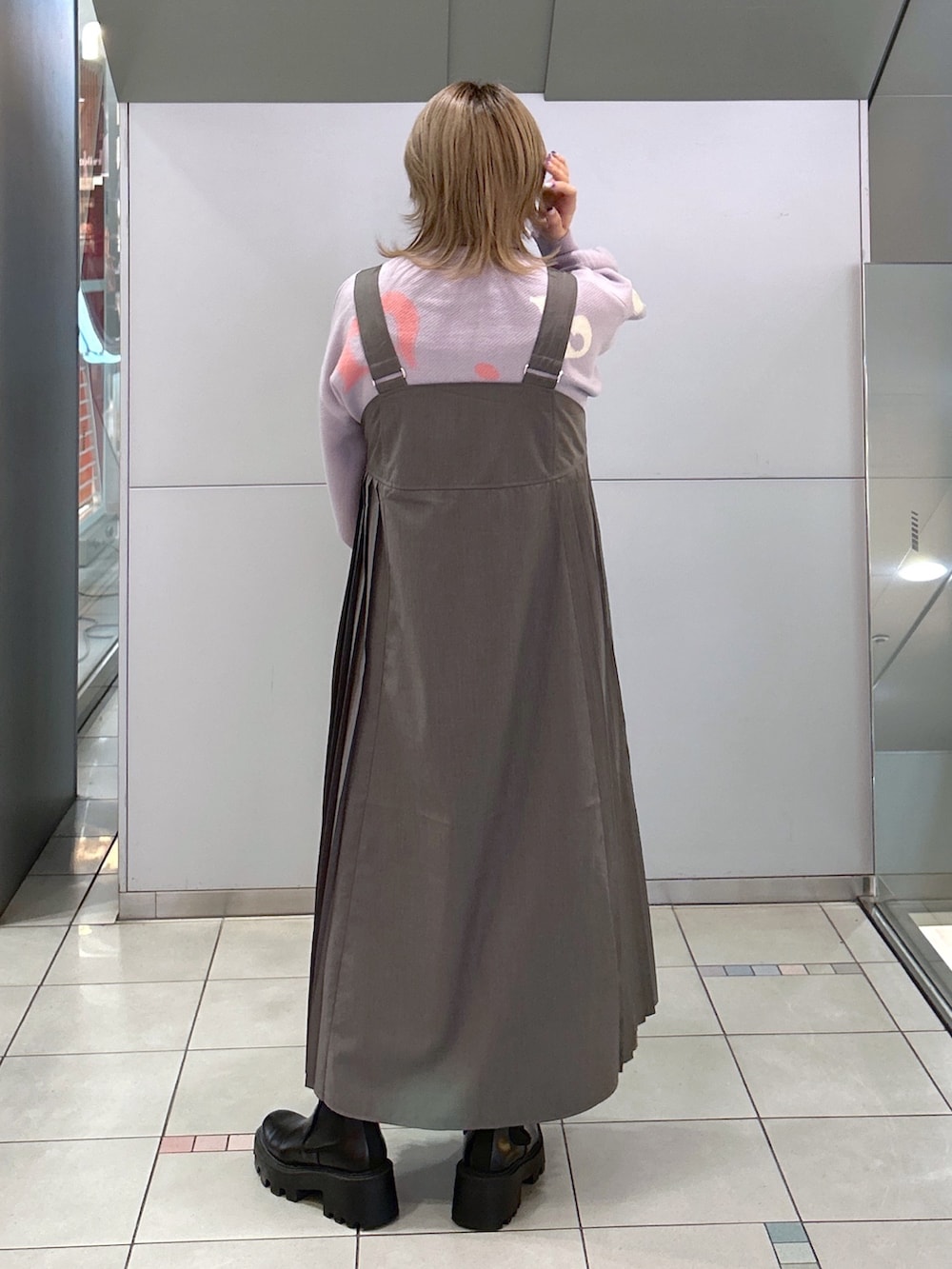 パープル系のニット/セーター、グレー系のジャンパースカート、ブラック系のショルダーバッグを着用したレディースの秋コーディネートの2枚目の写真