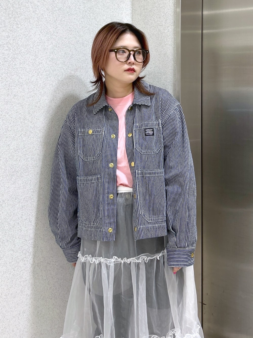 ホワイト系のスカート、ブラック系のデニムパンツ、ブラック系のブーツを着用したレディースの春コーディネートの5枚目の写真