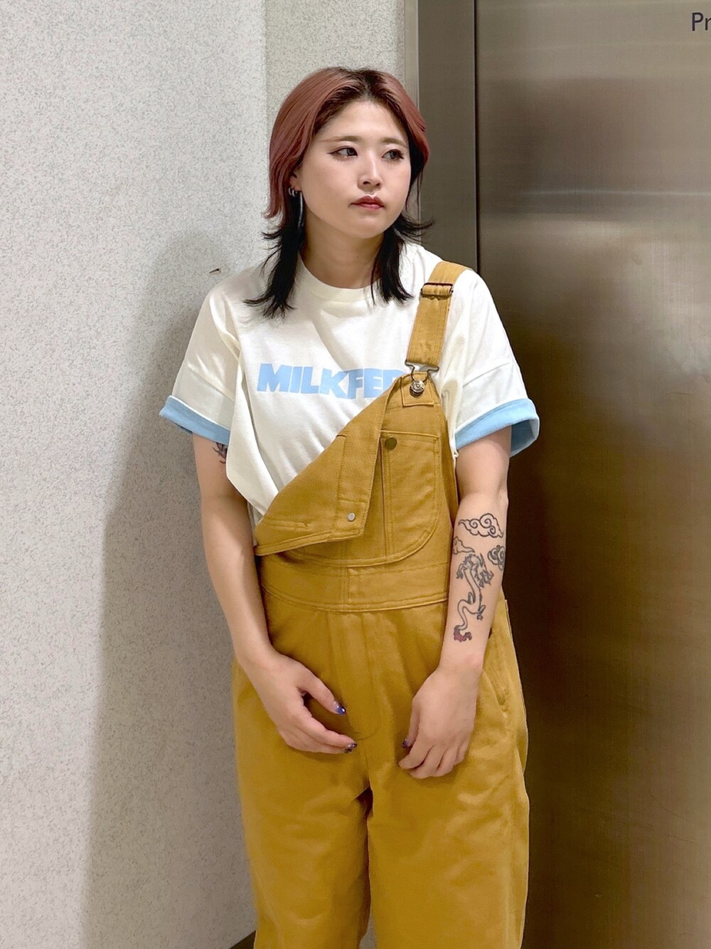 ベージュ系のサロペット/オーバーオール、ホワイト系のTシャツ/カットソー、ブラック系のブーツを着用したレディースの夏コーディネートの6枚目の写真