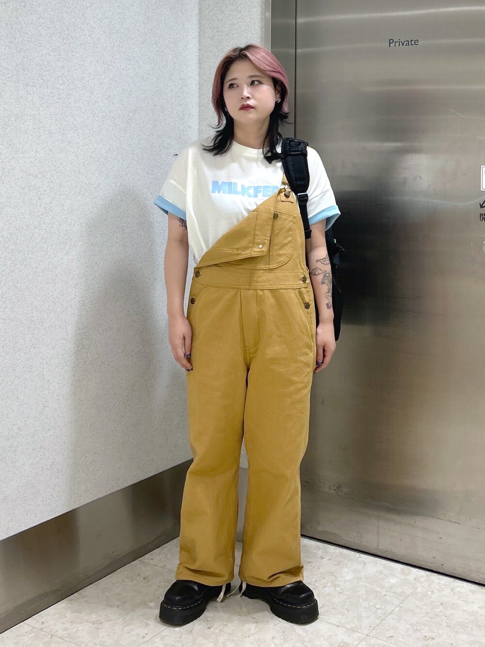 ベージュ系のサロペット/オーバーオール、ホワイト系のTシャツ/カットソー、ブラック系のブーツを着用したレディースの夏コーディネートの3枚目の写真