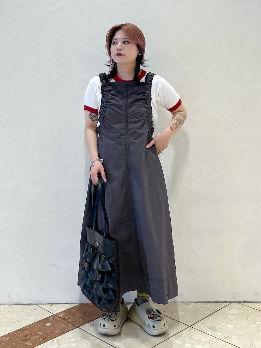 レッド系のTシャツ/カットソー、ベージュ系のサンダル、ブラック系のトートバッグを着用したレディースの春コーディネートの3枚目の写真