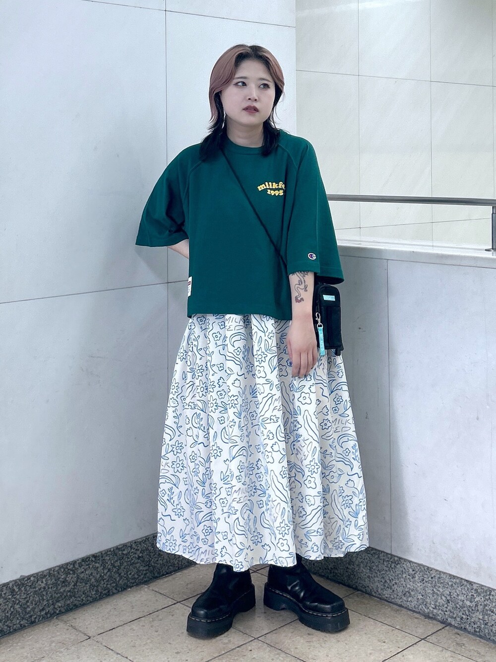 ホワイト系のワンピース、ブラック系のブーツ、グリーン系のショルダーバッグを着用したレディースの夏コーディネートの3枚目の写真