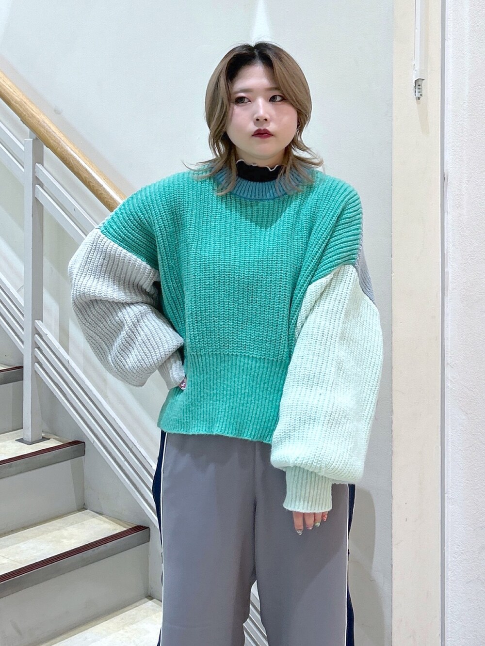 グリーン系のニット/セーター、ブラック系のショルダーバッグ、ブラック系のブーツを着用したレディースの冬コーディネートの5枚目の写真