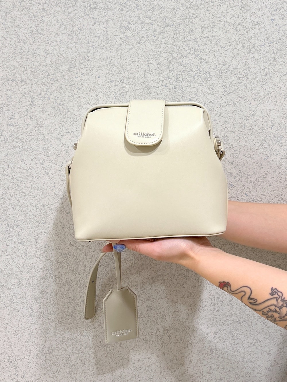 ブラック系のデニムパンツ、ホワイト系のショルダーバッグ、ブラック系のブーツを着用したレディースの春コーディネートの7枚目の写真