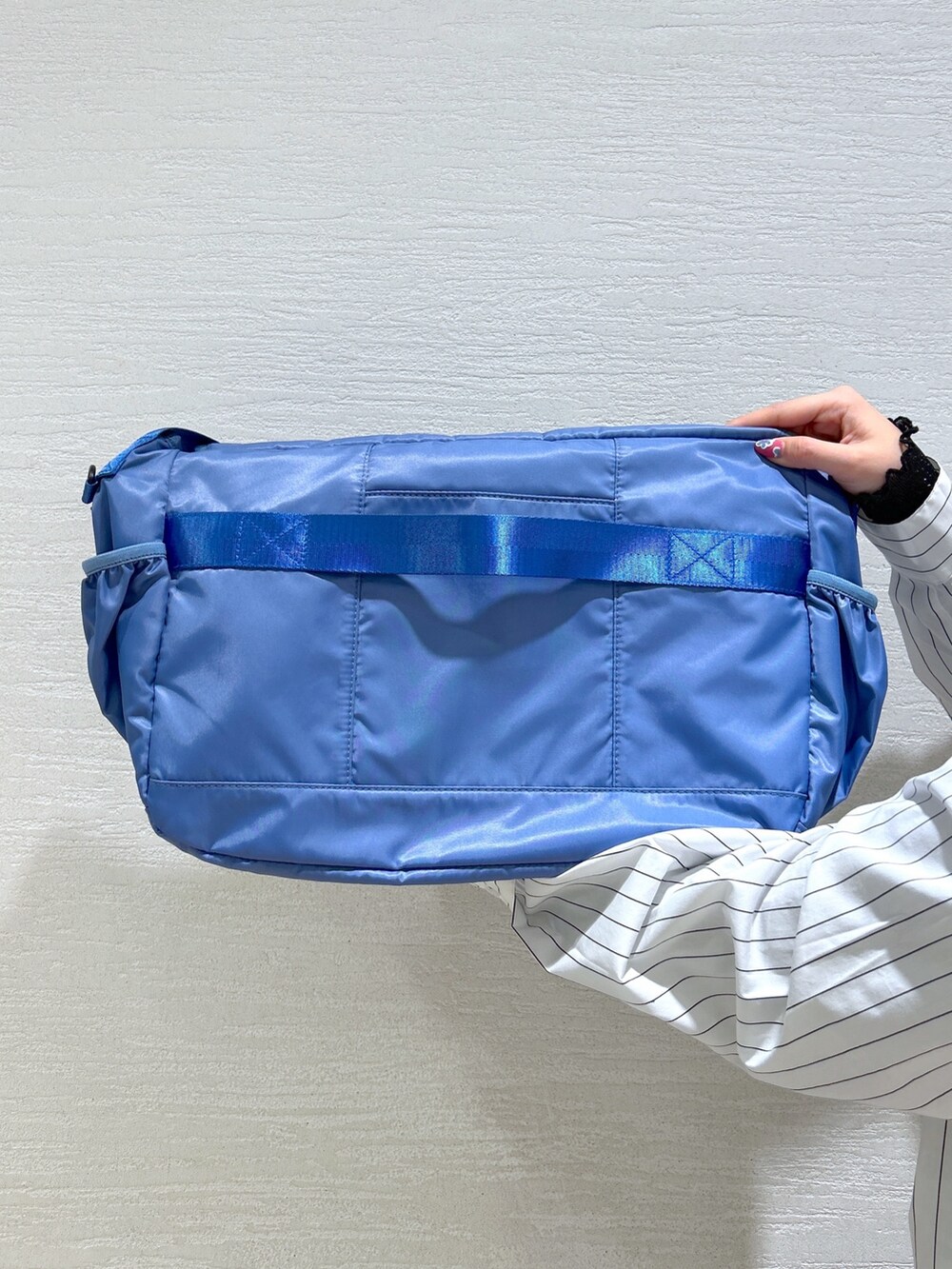 ホワイト系のシャツ/ブラウス、ブルー系のメッセンジャーバッグ、ブラック系のスウェットパンツを着用したレディースの冬コーディネートの10枚目の写真