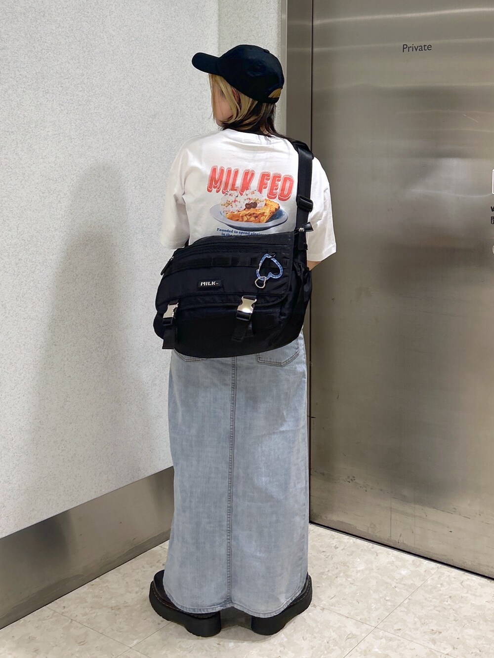 ホワイト系のTシャツ/カットソー、ブラック系のメッセンジャーバッグ、ブルー系のデニムスカートを着用したレディースの春コーディネートの4枚目の写真