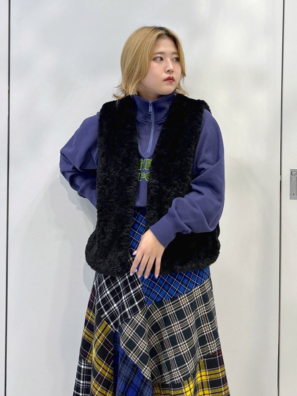 ブラック系のベスト、ブルー系のスウェット、ブラック系のスカートを着用したレディースの秋コーディネートの4枚目の写真