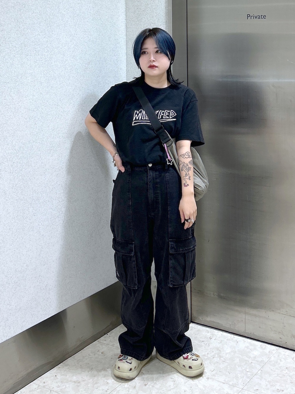 ブラック系のTシャツ/カットソー、ブラック系のカーゴパンツ、ベージュ系のショルダーバッグを着用したレディースの夏コーディネートの2枚目の写真